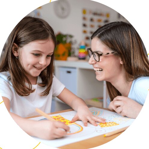 A therapist and a young girl laughing together over a drawing